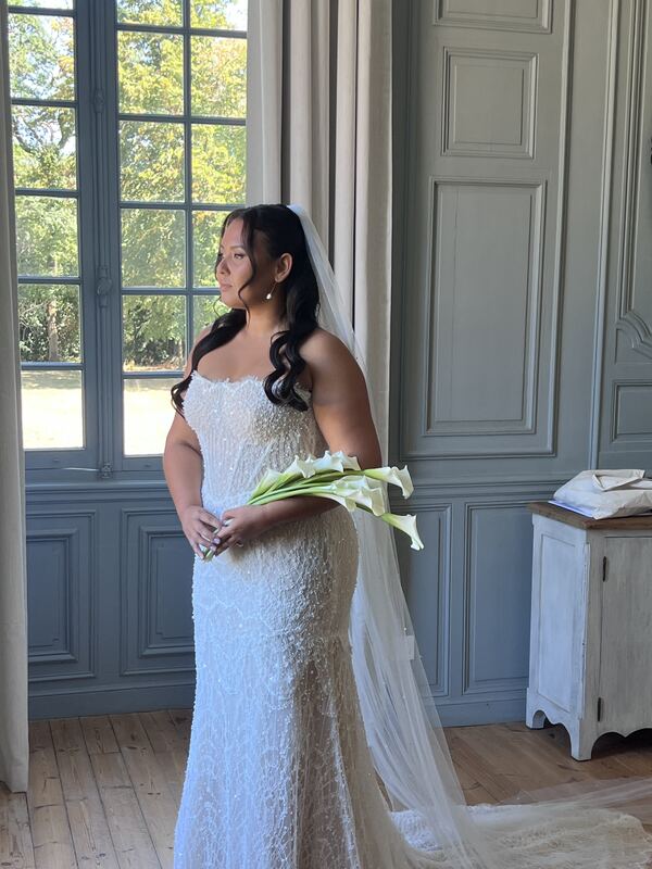 Mariée en robe de dentelle, bouquet de callas à la main.
