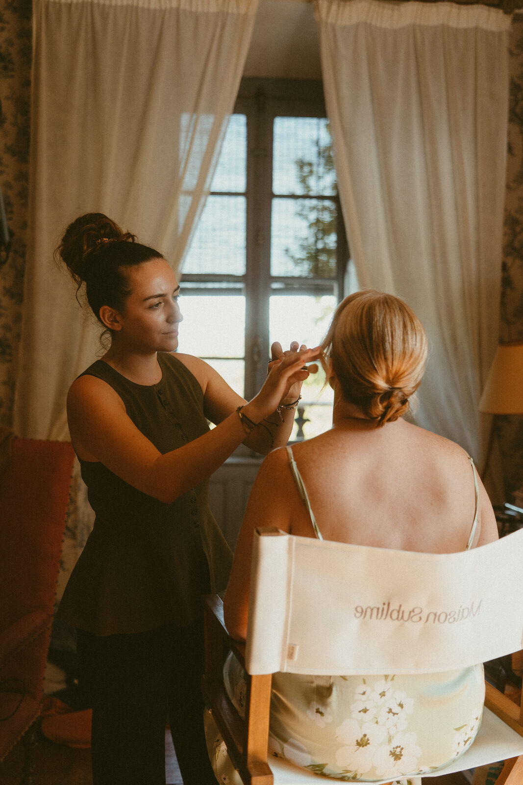Margaux coiffe et maquille une mariée pendant les préparatifs.
