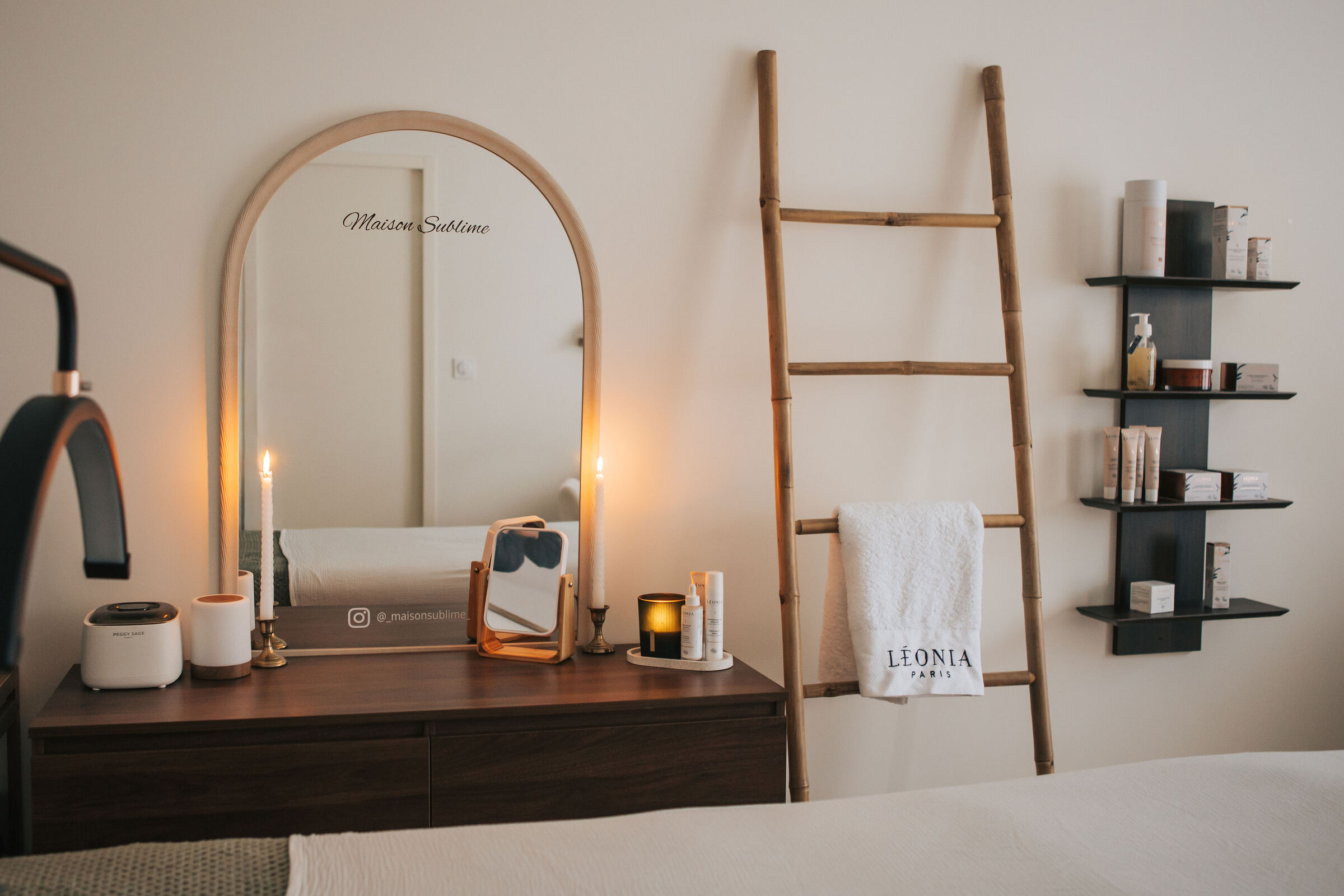 Le salon Maison Sublime : un miroir en arche, des bougies allumées, une échelle en bois et du linge Léonia.