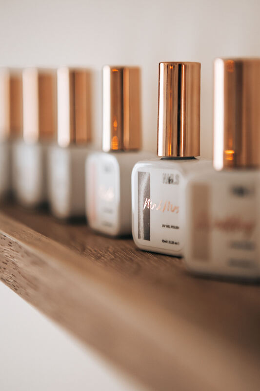 Flacons de vernis alignés sur une étagère en bois.